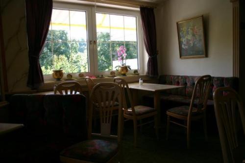 ein Esszimmer mit einem Tisch, Stühlen und einem Fenster in der Unterkunft Hotel Café Talblick in Vielbrunn