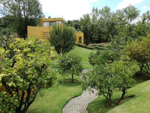 un jardín con árboles y un camino de piedra en Hotel Casa en el Campo en Morelia