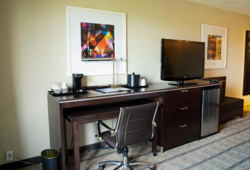 a desk with a television and a chair in a room at Holiday Inn Charlotte Airport by IHG in Charlotte