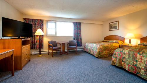 a hotel room with two beds and a television at Town and Mountain Hotel in Whitehorse