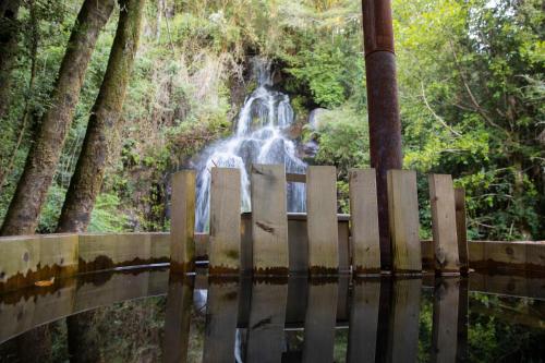 a waterfall over a wooden bridge with a fence at Pucura Eco Lodge in Licán Ray