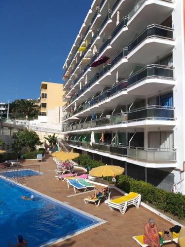 un hotel con sedie e ombrelloni accanto a una piscina di Playa del Ingles Cosy Apartment a Maspalomas
