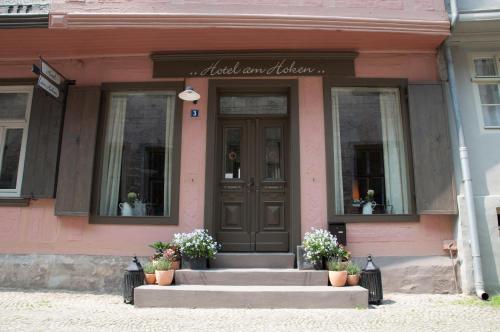 a front door of a pink building with flowers on the steps at Hotel am Hoken in Quedlinburg