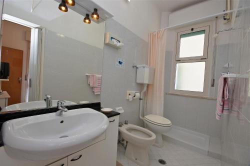 a white bathroom with a sink and a toilet at Hotel Victory in Cesenatico