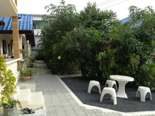 a patio with a white table and chairs and trees at Wattana Bungalow in Nai Yang Beach