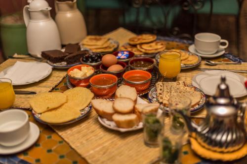 ein Tisch mit Tellern voller Essen, Eiern und Keksen. in der Unterkunft Riad Hala in Fès