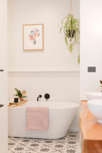 a bathroom with a white tub and a sink at Anzac North Loft - 4 Bedrooms & 2 Free Car Parks in Auckland