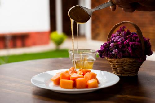 a person is pouring juice into a plate of fruit at Casa Tequio in San Cristóbal de Las Casas