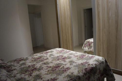 1 dormitorio con cama y espejo en Suíte para duas pessoas, en Itapema