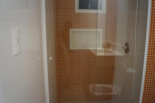 y baño con ducha de azulejos marrones. en Suíte para duas pessoas, en Itapema