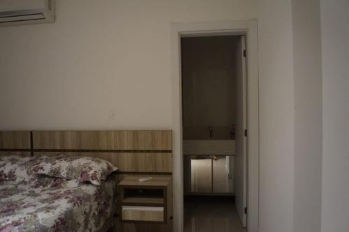 1 dormitorio con 1 cama y mesita de noche junto a una puerta en Suíte para duas pessoas, en Itapema