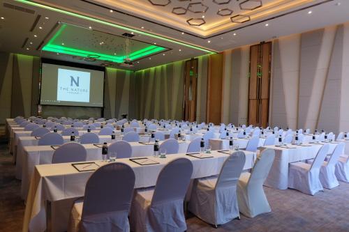 a conference room with white tables and chairs and a screen at The Nature Phuket - SHA Extra Plus in Patong Beach