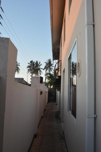 an alley between two buildings with palm trees in the distance at Triniti Airport Hotel in Dar es Salaam