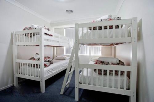 2 weiße Etagenbetten in einem weißen Zimmer in der Unterkunft Jindabyne Executive in Jindabyne