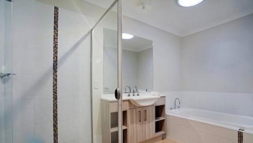 a bathroom with a shower and a sink and a tub at Jindabyne Executive in Jindabyne