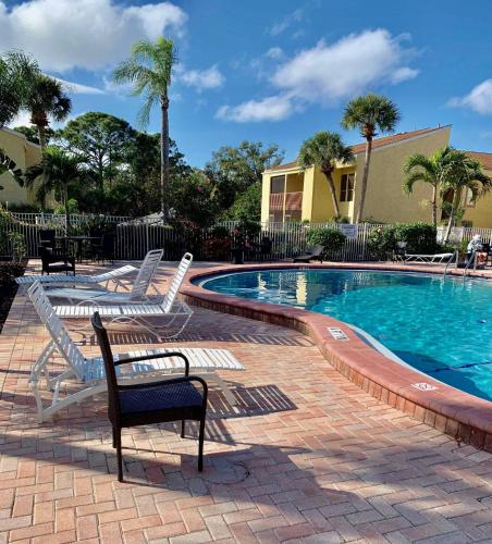 a swimming pool with white chairs next to a building at Sienna Park Apartments in Sarasota