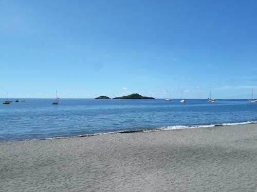 a beach with boats in the water and sailboats at Les Gites Capra - Papaye in Bouillante