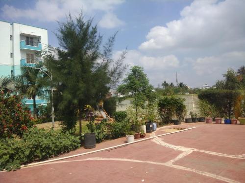 a parking lot with trees and plants in front of a building at Gerones Residency Serviced Apartments & Home Stays in Coimbatore