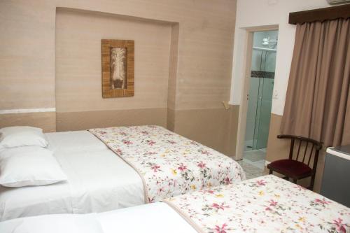 a bedroom with two beds and a picture on the wall at Hotel Morada do Mar in Guarujá