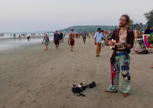 a man standing on the beach next to a bag on the beach at Angelo's place in Arambol