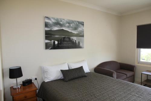 a bedroom with a bed and a chair and a television at Tumut Apartments in Tumut
