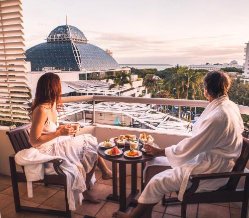 two people sitting on a balcony with food on a table at Pullman Reef Hotel Casino in Cairns