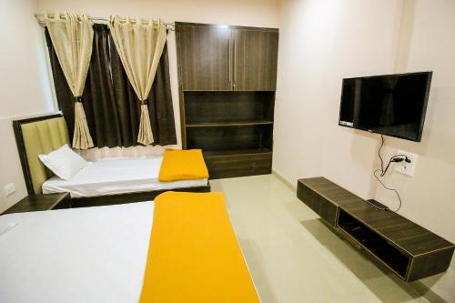 Cette chambre comprend un lit et une télévision à écran plat. dans l'établissement Namastay Welcome Home, à Ratlām