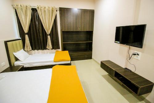 a room with a bed and a flat screen tv at Namastay Welcome Home in Ratlām