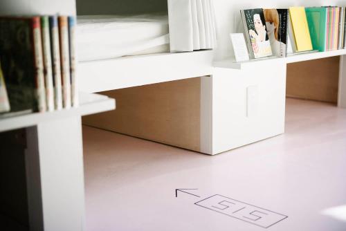 a white book shelf with books on it at MANGA ART HOTEL, TOKYO in Tokyo