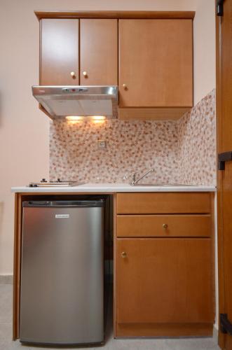 a kitchen with wooden cabinets and a stainless steel refrigerator at Orama Studios in Agia Anna Naxos