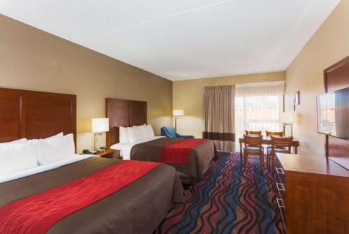 a hotel room with two beds and a desk at Baymont by Wyndham Bonita Springs in Bonita Springs