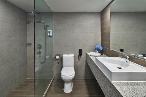 a bathroom with a toilet and a sink and a shower at RELC International Hotel in Singapore