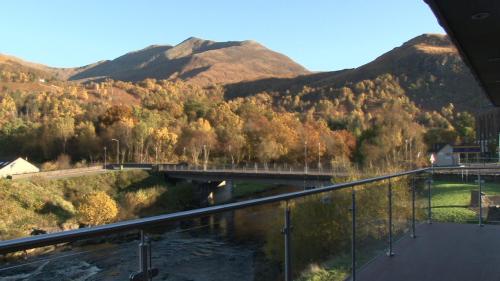 a bridge over a river with mountains in the background at Highland Getaway in Kinlochleven
