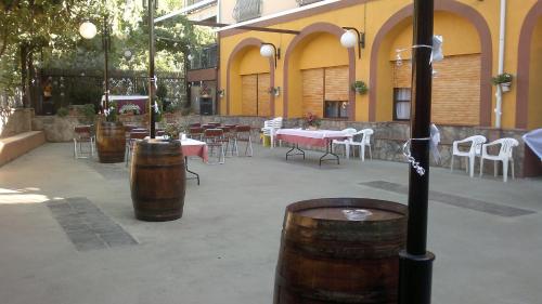 a patio with tables and chairs and barrels at Hostal Restaurante Solaire in Castañar de Ibor