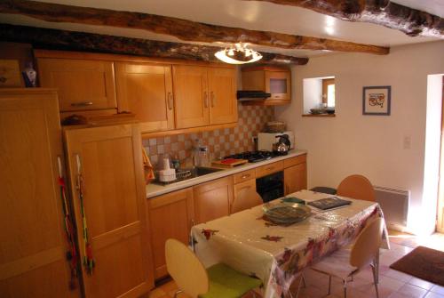 a kitchen with wooden cabinets and a table with chairs at Quercy Stone Gite Marcilhac in Marcilhac-sur-Célé