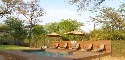 a patio with chairs and umbrellas next to a pool at Sandpiper Villas Chobe in Kasane