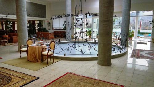 un vestíbulo con una gran bañera con mesa y sillas en Arta Palace, en Árta