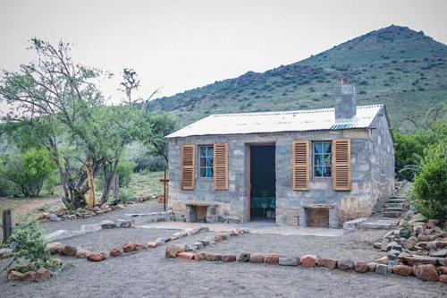a small stone house in front of a mountain at Waterval farmstay in Graaff-Reinet