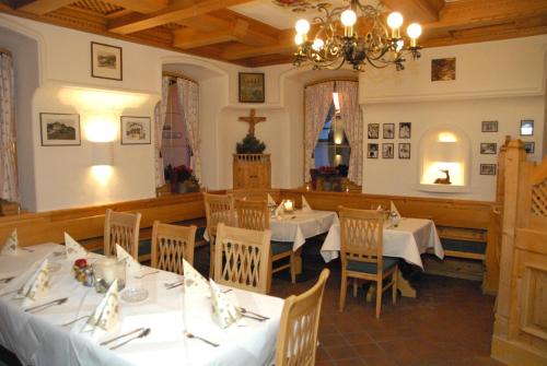 キルヒベルク・イン・チロルにあるホテル ブロイヴィルトの白いテーブルと椅子、シャンデリアのあるレストラン