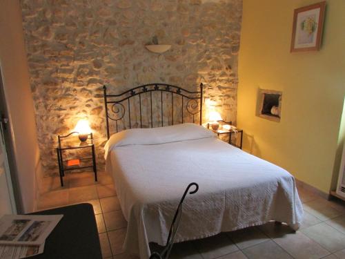 La Bastide Des Senteurs في Saint-Victor-de-Malcap: غرفة نوم بسرير وجدار حجري