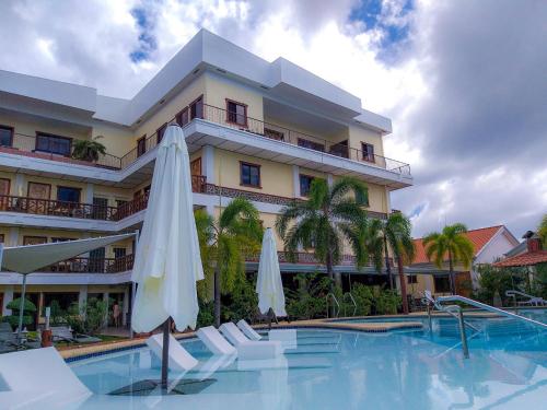 パングラオにあるSunville Hotel and Restaurantのスイミングプール、白い傘2本が備わるホテルです。