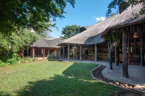 ein Haus mit einem Strohdach und einem Hof in der Unterkunft Munga Eco-Lodge in Livingstone
