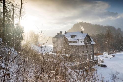 a large building in the snow with the sun behind it at Apart Hotel Wetterhorn in Hasliberg
