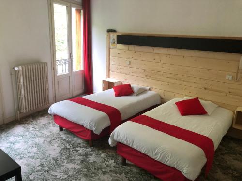 a room with two beds with red and white sheets at Aparthotel Le Petit Train in Luchon