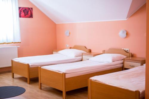 3 Betten in einem Zimmer mit orangefarbenen Wänden in der Unterkunft Guesthouse Beno in Starše