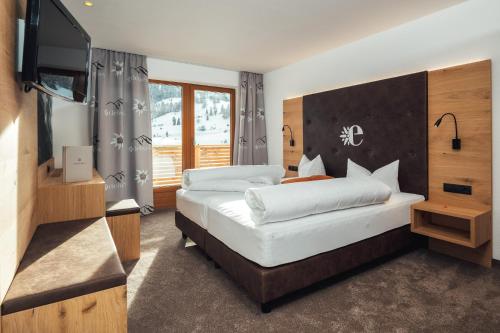 a bedroom with two beds and a flat screen tv at Hotel Edelweiss Superior in Nauders