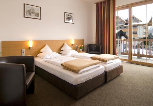 a hotel room with two beds and a large window at Hotel Bräuwirt in Kirchberg in Tirol