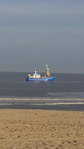 a large blue ship in the ocean near a beach at Villa Zeezicht in Noordwijk