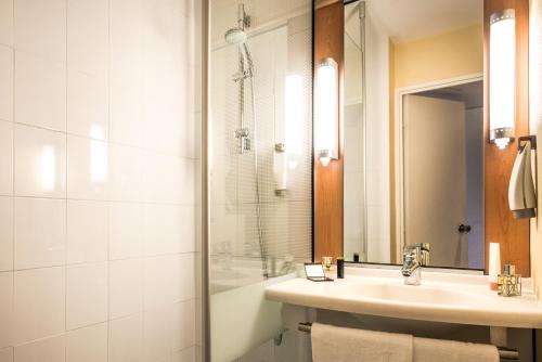La salle de bains est pourvue d'un lavabo et d'une douche. dans l'établissement ibis Paris Montmartre Sacré-Coeur, à Paris