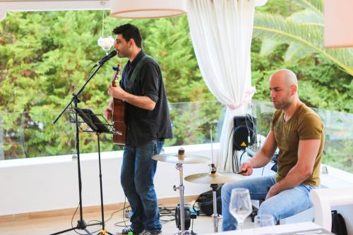two men playing drums and a man playing a guitar at Mandraki Village Boutique Hotel in Koukounaries
